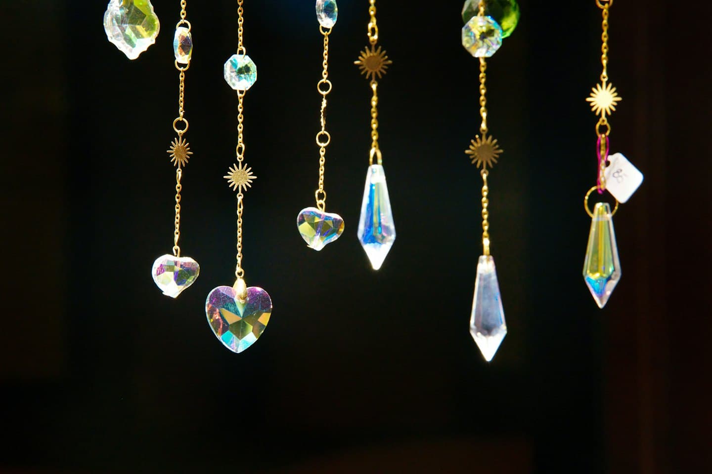 Iridescent crystal suncatchers hanging from delicate golden chains.