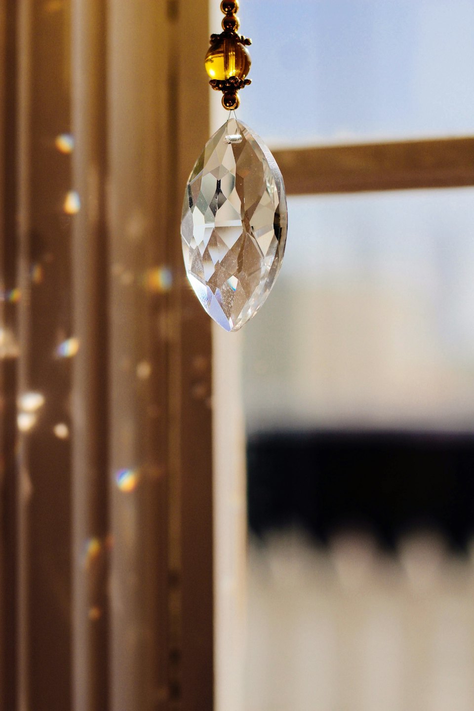 Crystal suncatcher refracting rainbow light indoors near a window.