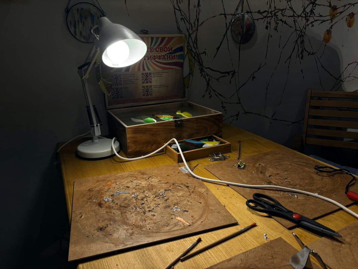 Stained glass supplies and tools sit on a wooden workbench.