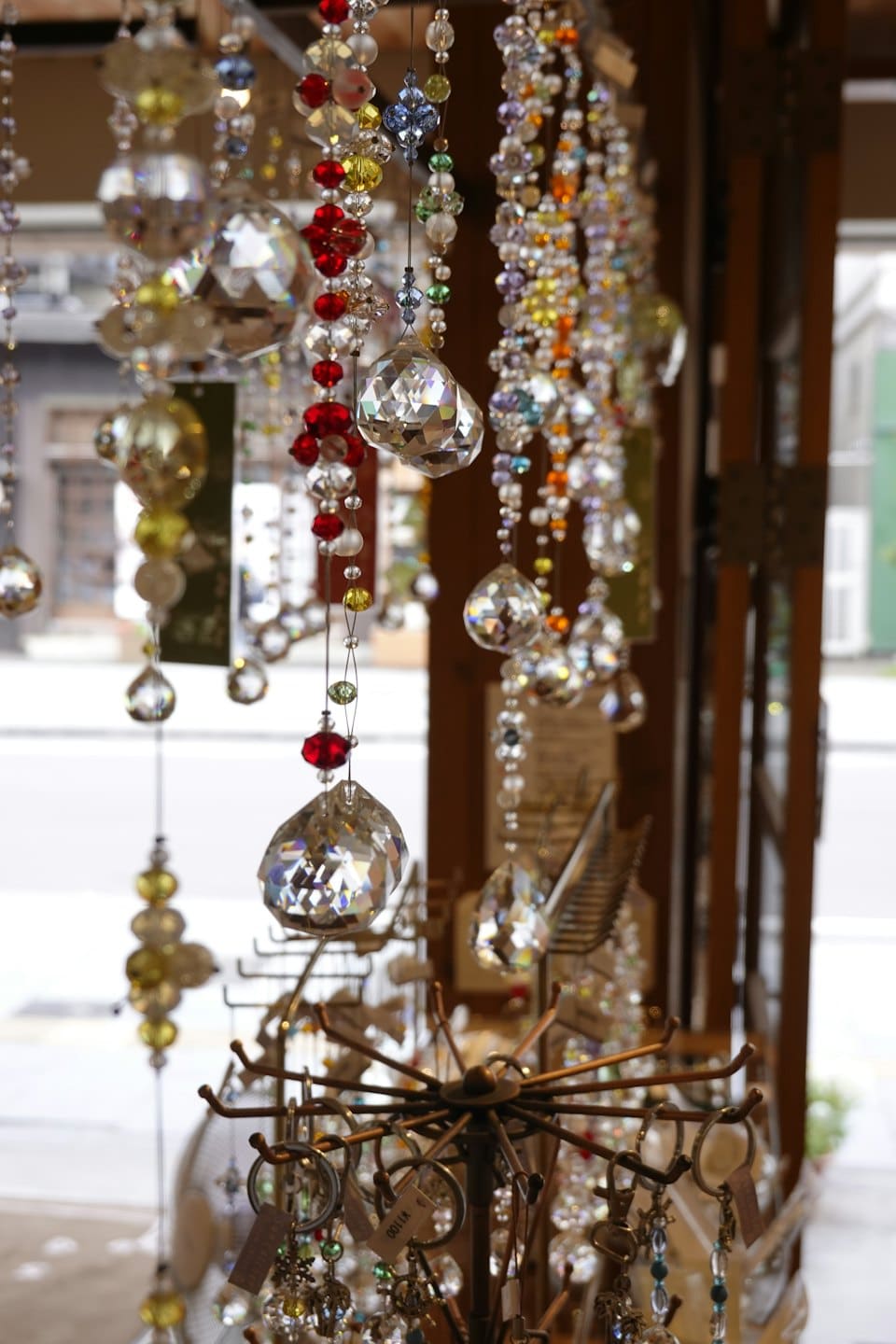 Crystal suncatchers and glass keychains hanging on a store stand.