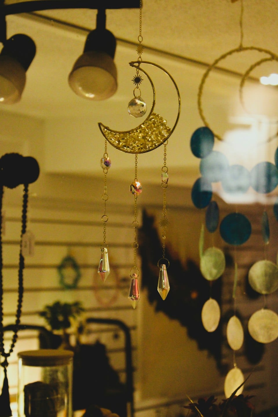 Crescent moon suncatcher with crystals hanging in a shop display.